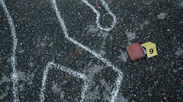 Chalk outline on pavement with number tag and wallet next to it