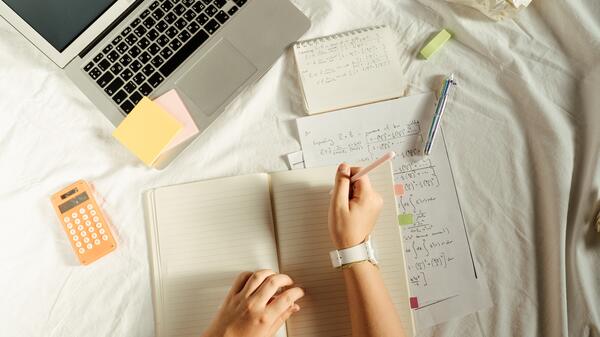 Person working on school work in bed