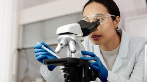Woman looking into a microscope in a lab.