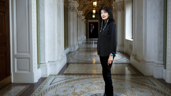 U.S. poet laureate Joy Harjo standing in an ornately decorated hallway.