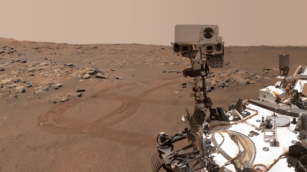 A "selfie" of the Perseverance Mars rover showing the rover on the right side of the image and the barren Martian landscape behind it.