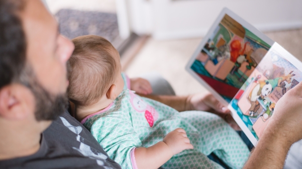 A father reads out loud to his baby.