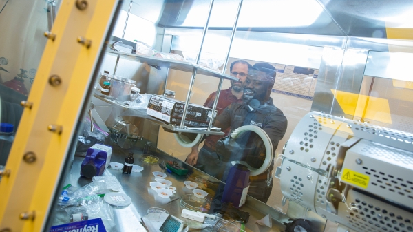 Graduate Research Associate Emmanuel Dasinor conducts research in Assistant Professor Bruno Azeredo's lab, surrounded by machinery.