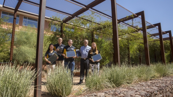 A group of people stands outside holding small solar panels