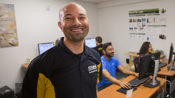 Portrait of Rod Roscoe in a computer lab. Caption "Rod Roscoe, assistant professor of human systems engineering, works with students in his SLATE Lab to improve engineering education