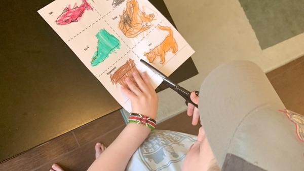 Boy in a hat cutting squares in a piece of paper