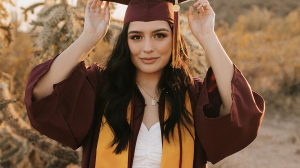 ASU grad Priscilla Terry in her ASU cap and gown in a desert landscape