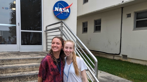 ASU students Sadie Cullings and Noelle Geddis pose in front of a building with a NASA logo on it.