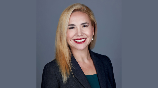 Rachele Peterson smiles at the camera in this professional headshot. She has blonde shoulder length hair. Is wearing a dark blazer and has bright red lipstick.