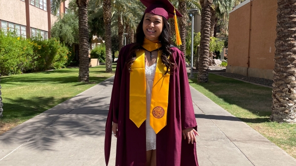 ASU graduate Sami Shah wearing a maroon graduation cap and gown surrounded by palm trees on the Tempe campus.