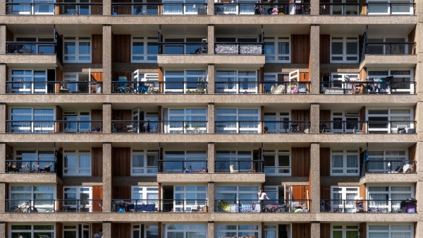 Exterior of an apartment building showing several balconies with a variety of furniture and some people.