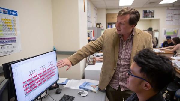 Man pointing to a computer screen that a student is looking at.