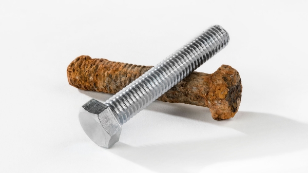 A rusty screw and a new screw show the destruction of corrosion on metal and metal alloys.