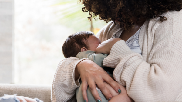 A mother holds her infant while breastfeeding.