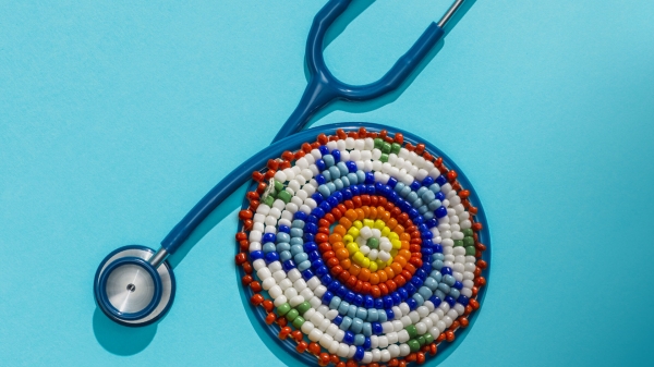 A stethoscope with an Indigenous beading pattern in the middle against a teal background