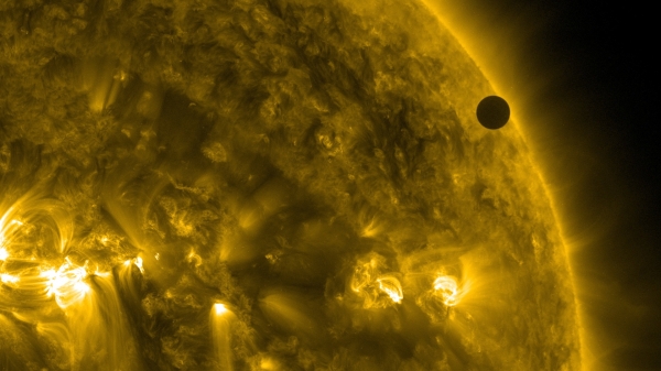 A close up of the sun as the planet Venus appears as a small black dot in front of the sun