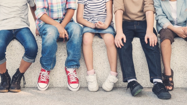 Children shown from the shoulders down, seated on a step.