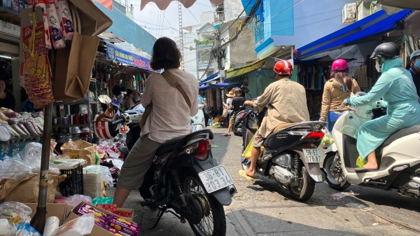 People driving motor bikes next to stalls and vendors in Vietnam