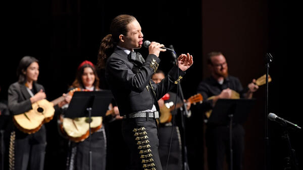 Man singing in front of a group of musicians.