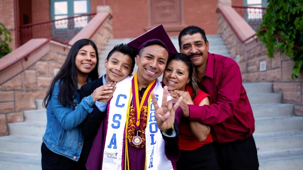 An ASU graduate in cap and gown poses with his siblings and parents at Old Main on ASU's Tempe campus