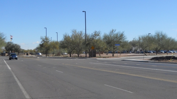 A wide street with a car in the distance driving toward the vantage point.