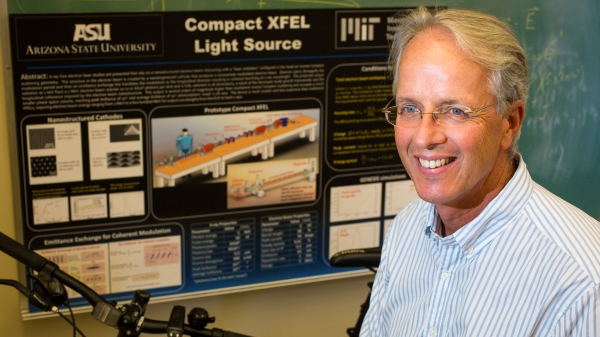 Man poses in front of an X-ray laser display poster