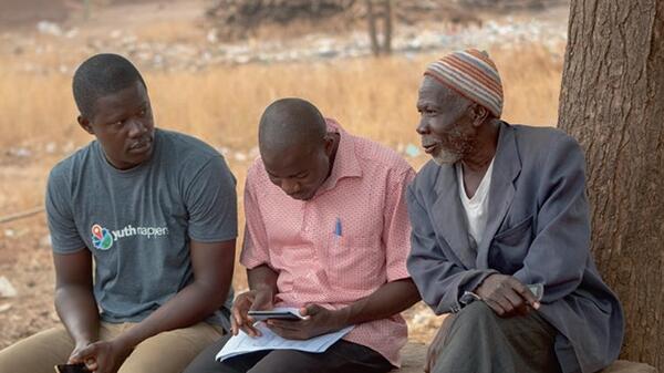 Three students in the YouthMapper network sitting together in an outdoor setting.