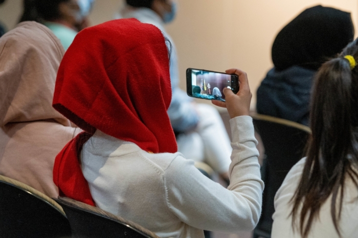 A young woman takes a cellphone photo during the welcome gathering for more than 60 young women from Afghanistan