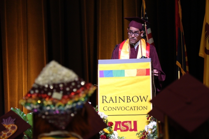 Man standing behind a lectern speaking into a microphone at ASU's Rainbow Convocation.