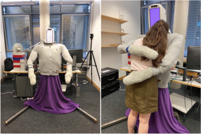 A researcher receives a hug from HuggieBot