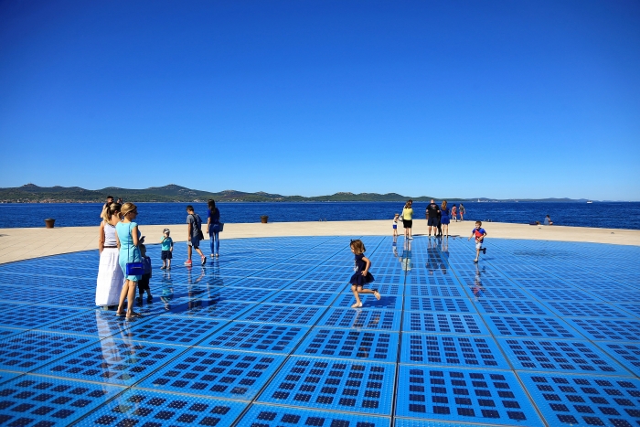 People walking on a glass floor with solar panels underneath