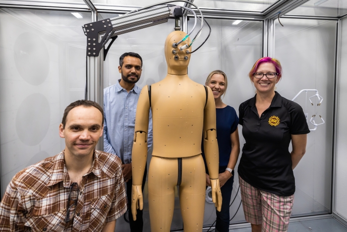 Group of researchers posing around heat-sensing manikin