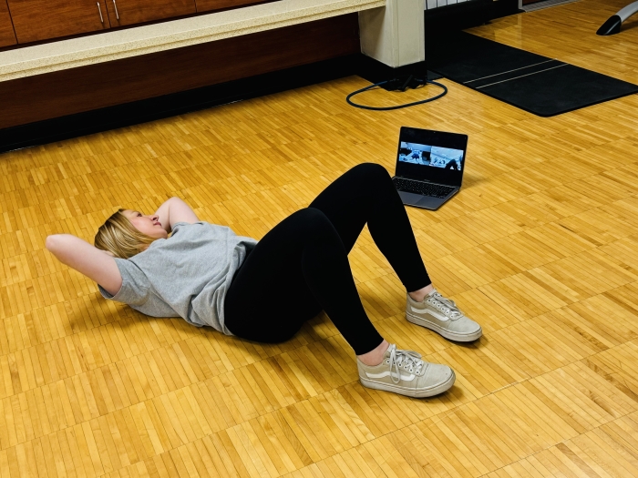 Woman lying on the floor looking at a laptop screen.