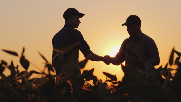 Silhouette image of two farmers shaking hands