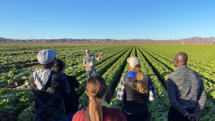 A diverse group of students receive instruction in an agricultural field