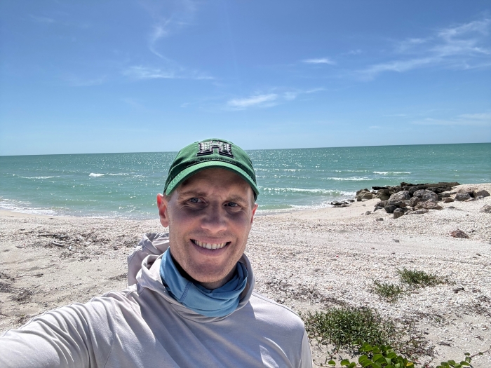 Selfie of man in hoodie and baseball cap on the beach