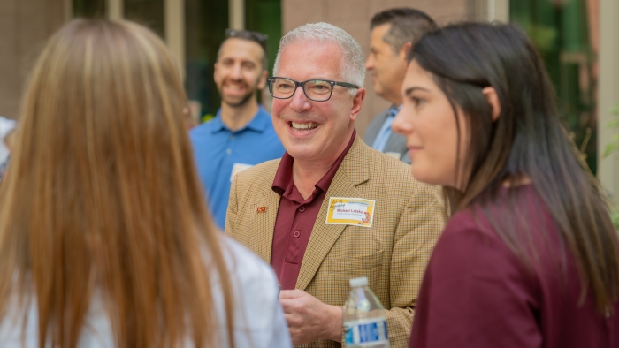 A man smiles talking to a group of people