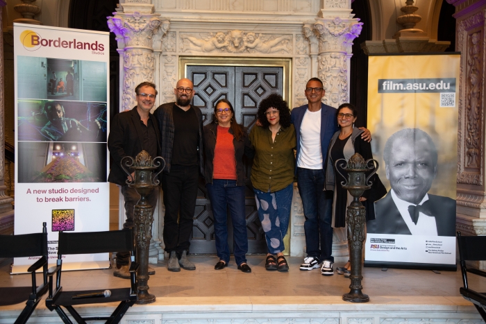 Six people pose for a group photo in between banners about Borderlands Studios and the ASU film school