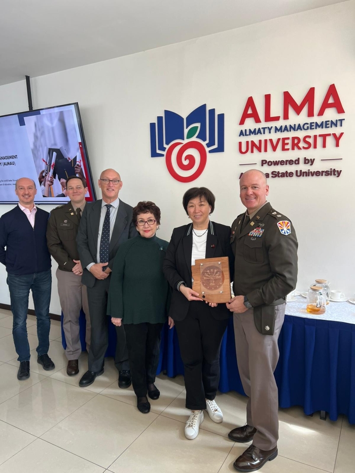 Group photo at Almaty Management University receiving a plaque from the State Partnership Program.