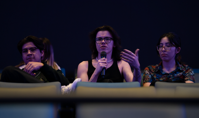 Student seated in an auditorium speaking into a microphone.