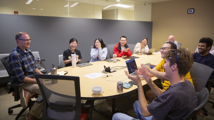 Ross Maciejewski works at a table with a group of students.