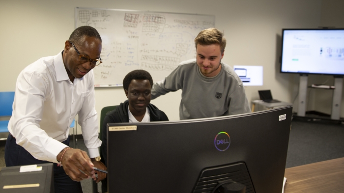 Kinsy works with students at a computer.