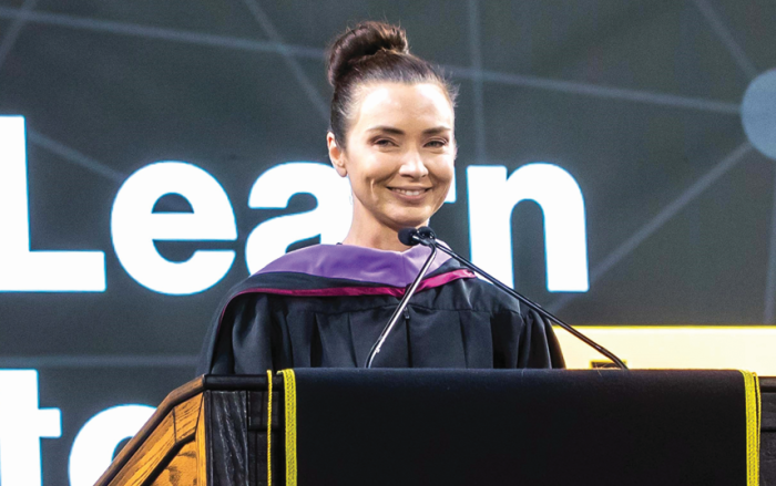 A woman stands smiling in front of a podium.