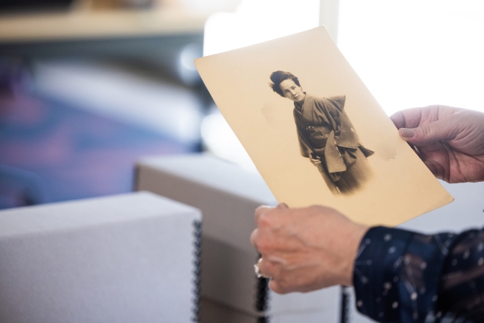 Hands holding out a historical, black and white photo of a Japanese woman in traditional dress