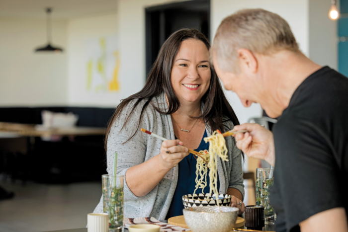 A man and a woman eating bowls of ramen noodles together