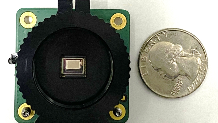 The chip-integrated polarimetric imaging sensor next to a quarter demonstrates its compact size