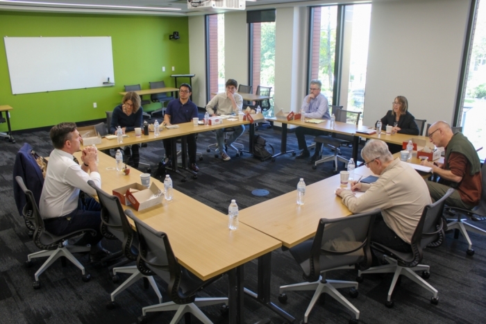 People seated at tables speaking in a classroom.