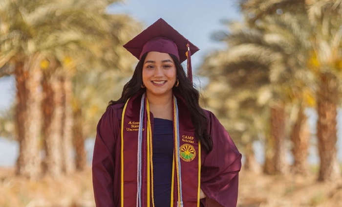  poses in an outdoor setting wearing her graduation gown, cap and stole.