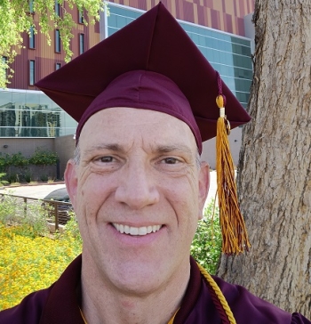 Man smiling with a graduation cap