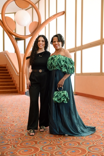 Photo of Sarah Abdallah with Colleen Jennings-Roggensack inside ASU Gammage.  Jennings-Roggensack is wearing the two-toned green dress designed by Abdallah.